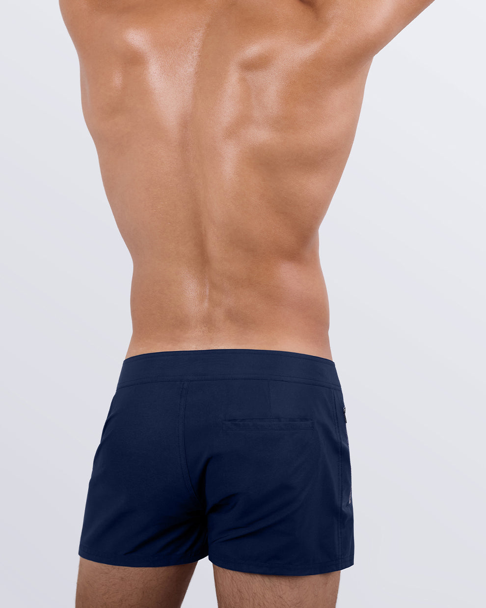 Male model wearing men’s NAVY BOOMER Beach Shorts swimsuit in a dark denim blue color, complete the back zippered pocket, made by DC2 a capsule brand by BANG! Clothes in Miami.