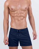 A male model wearing the NAVY BOOMER - Flex Shorts by DC2 Miami. These premium shorts feature a deep navy blue shade with a stylish lace-up front and water-resistant metallic zippers.