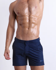 Male model wearing NAVY BOOMER swimming Tailored Shorts, in a dark denim blue color for men. These premium quality swimwear bottoms are by BANG! Clothes, a men’s beachwear brand from Miami.