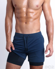 View of men’s durable training shorts in a solid navy color with black compression shorts made by DC2, the official brand of men’s sportswear.