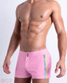 Side view of the PADAM PINK men’s summer Beach Shorts, with dual zippered pockets. The shorts are in a solid light pink color with side yellow and aqua stripes for men made by DC2 a brand based in Miami.