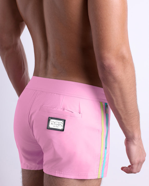 Side view of the PADAM PINK men’s summer Beach Shorts, with dual zippered pockets. The shorts are in a solid light pink color with side yellow and aqua stripes for men made by DC2 a brand based in Miami.