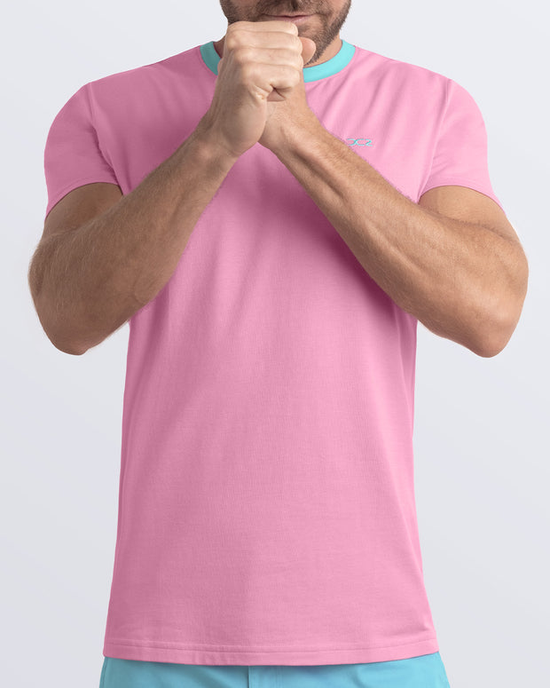 A model wearing the PADAM PINK, a light pink Pima cotton t-shirt with a light aqua collar, showcasing the breathable, lightweight fabric ideal for summer beachwear and street style. Part of the DC2 Miami men&