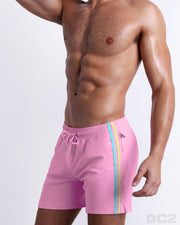 Side view of the PADAM PINK for men’s summer Resort Shorts with dual zippered pockets in a solid light pink color with side aqua and pastel yellow stripes for men. These premium quality swimwear bottoms are DC2 by BANG! Clothes, a men’s beachwear brand from Miami.