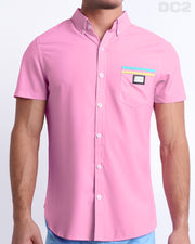 This is a front view of a male model looking sexy in a PADAM PINK stretch shirt for men. The shirt is light pink with yellow and aqua-colored stripes on the left pocket. It's a premium quality button-up top made by DC2, a Miami-based men's beachwear brand.