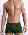 Male model wearing the PALM GREEN Mini Shorts, premium swimwear in a solid dark green color for men. These high-quality swimwear bottoms by DC2, a men’s beachwear brand from Miami.