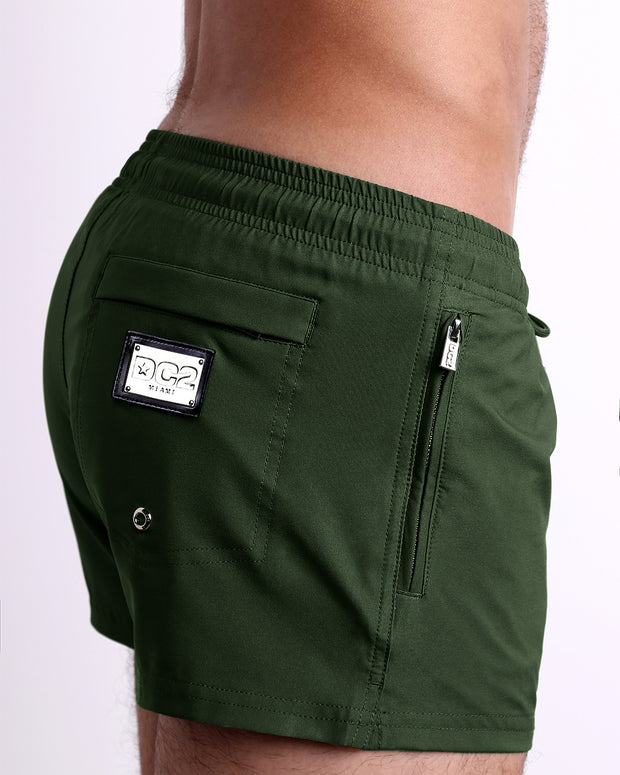 Side view of the PALM GREEN swimsuit Poolside Shorts men’s shorter length shorts with side zipper pocket featuring a dark green color. These high-quality swimwear bottoms by DC2, a men’s beachwear brand from Miami.