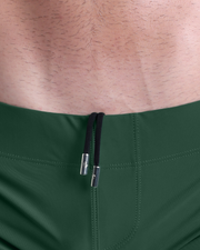 Close-up view of men’s summer beach shorts by DC2 clothing brand, showing black cord with custom branded metallic silver cord ends.