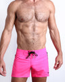 Frontal view of sexy male model wearing the PINK BOMB men’s flex shorts featuring a hot pink color by the Bang! brand of men's beachwear from Miami.