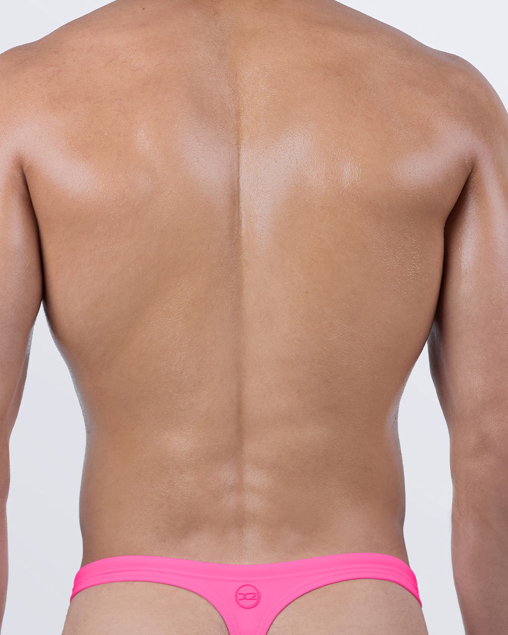 Back view of DC2 PINK BOMB swim thong for men, featuring a T-back design for ideal tan lines and ultra-light coverage.