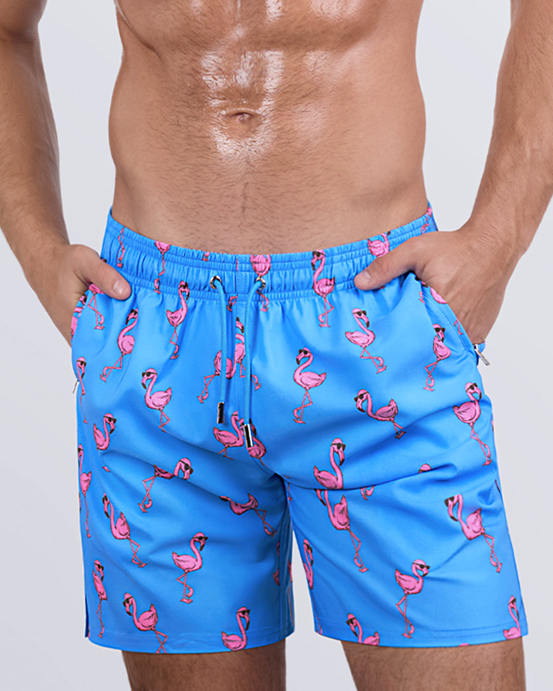 Close-up side view of a male model in the PINK FLAMINGOS Resort Shorts for men by DC2 Miami. These stylish swim shorts feature premium four-way stretch fabric, metallic zip pockets for secure storage, and water-resistant properties for a seamless transition from the beach to the streets.