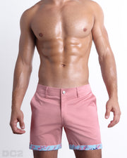 Front view of a male model wearing PINK ILLUSIONS men's chino shorts in a solid light pink color with reversible cuff that reveals DC2® signature print when flipped out. Designed by DC2 a BANG! Miami Clothes capsule brand.