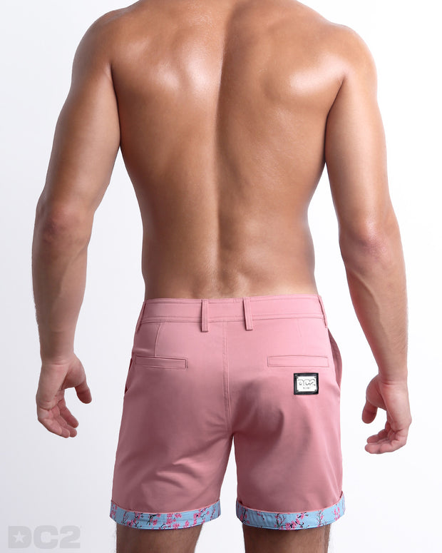 Back view of a model wearing woven twill cotton chino shorts in a light pink color for men. These premium quality swimwear bottoms are DC2 by BANG! Clothes, a men’s beachwear brand from Miami.
