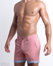 Side view of stretchy men's shorts in PINK ILLUSIONS a bright vibrant light pink color with with two front pockets and custom engraved button front closure with zip fly from DC2. 