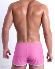 Back view of male model wearing the PINKTYQUE beach Swim Shorts for men by BANG! Miami in a solid vibrant pink color.