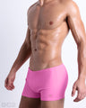 Side view of a masculine model wearing men’s swimsuit compression shorts in a pink color featuring a side pocket with official logo of DC2 Brand.