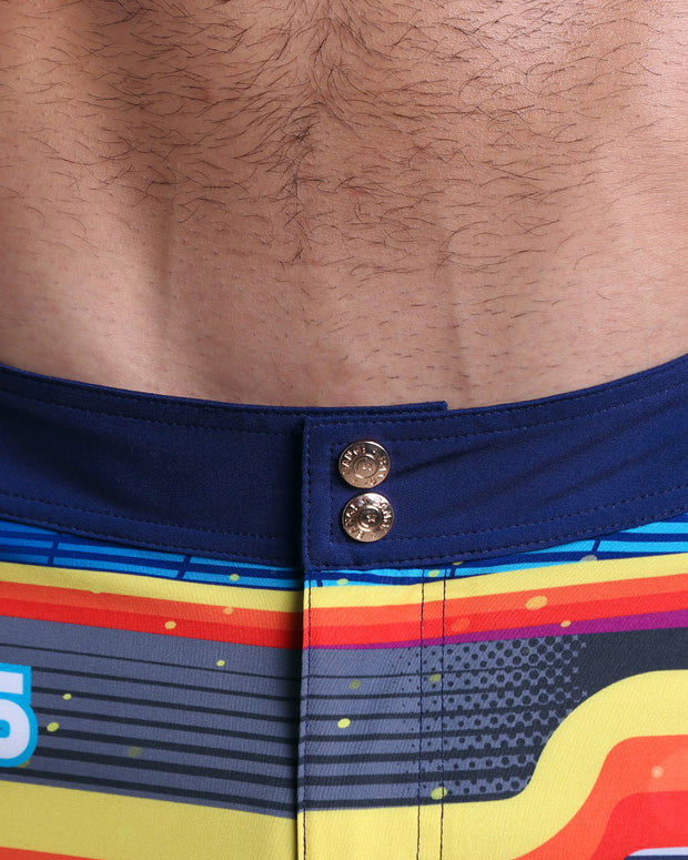 Close-up view of inseam and details of POOL POSITION swimsuit for men, showing custom branded golden buttons.