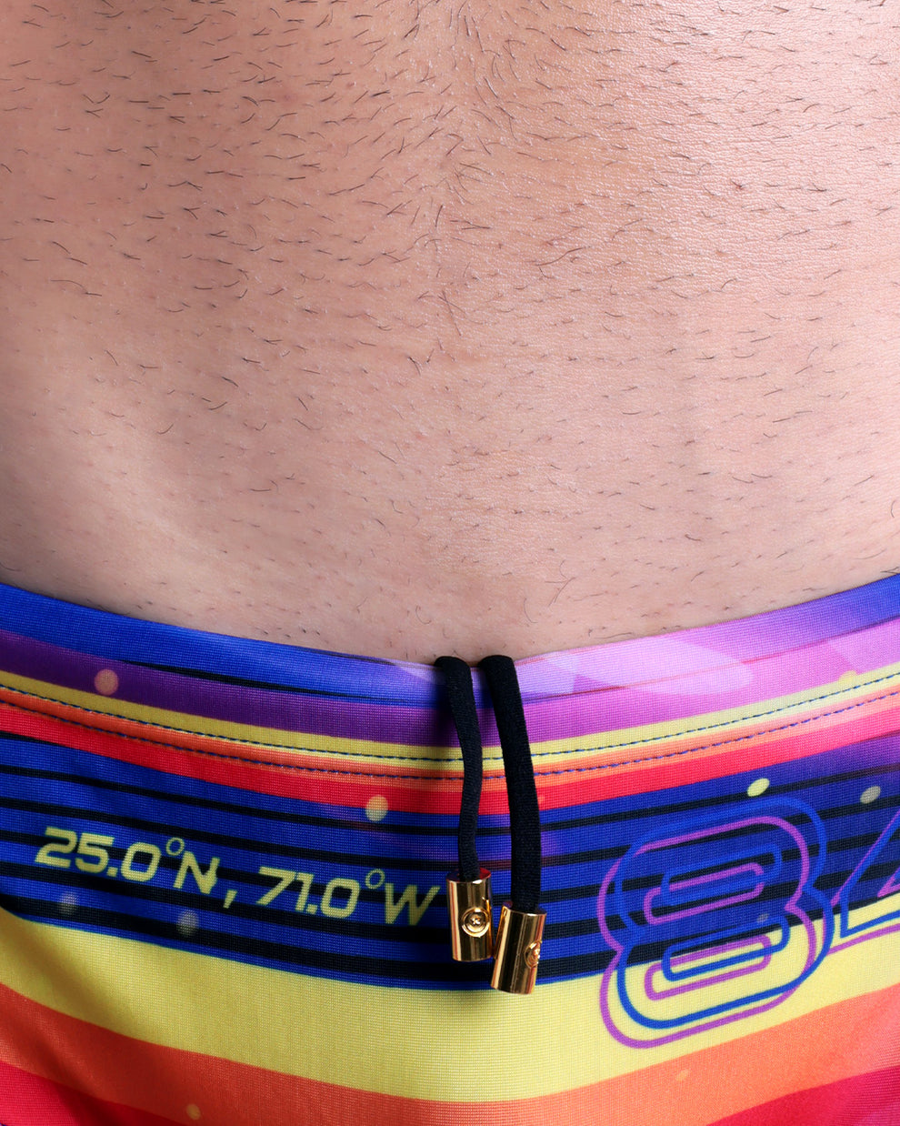 Close-up view of the POOL POSITION men’s drawstring briefs showing black cord with custom branded golden cord ends, and matching custom eyelet trims in gold.