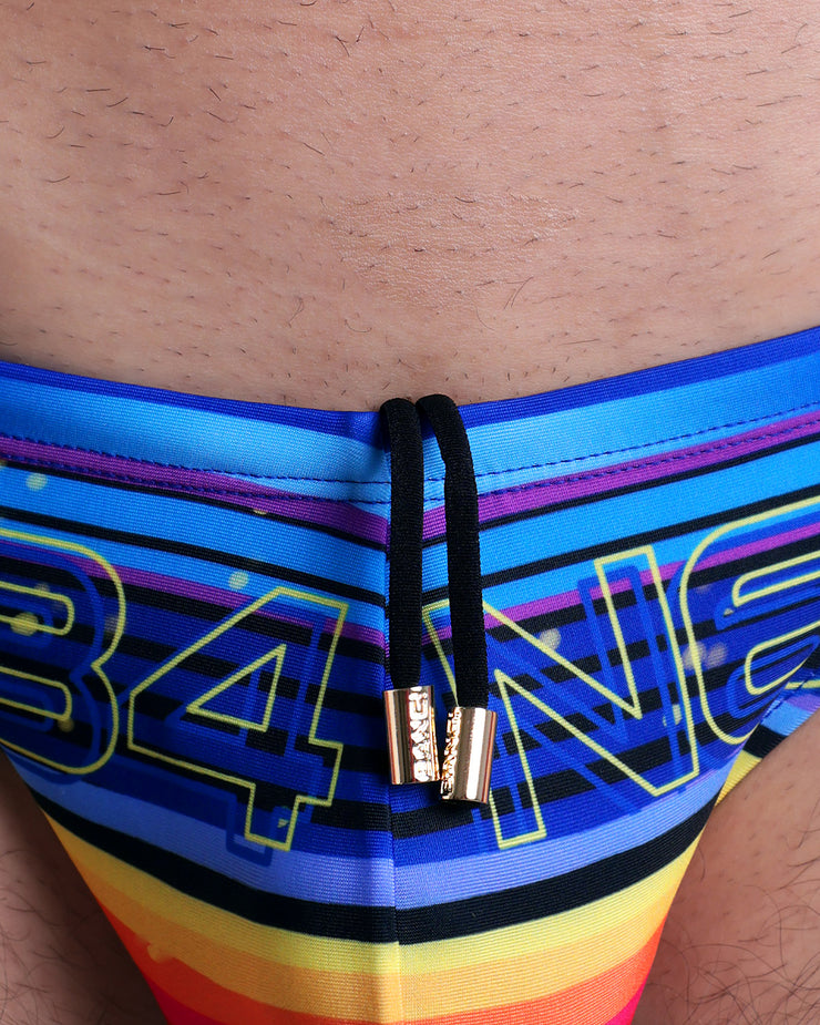 Close-up view of the POOL POSITION men’s drawstring briefs showing black cord with custom branded golden cord ends, and matching custom eyelet trims in gold.