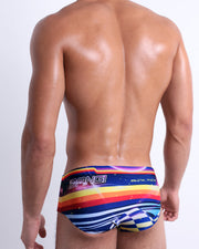 Back view of a model wearing POOL POSITION men’s beach sexy Brazilian Swim Sunga featuring a colorful design that pays homage to motorsports and Grand Prix racing, designed by BANG! Clothes in Miami.