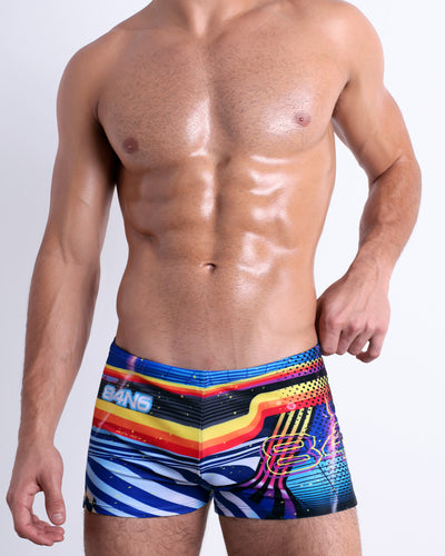 Front view of the POOL POSITION men’s Swim Trunks featuring dynamic colors, including shades of blue, red, yellow, and orange - inspired from the iconography of racing car graphics. This premium quality swimwear is by BANG! Clothes, a men’s beachwear brand from Miami.