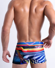 Back view of a model wearing POOL POSITION men’s beach sexy Swim Trunks featuring a colorful design that pays homage to motorsports and Grand Prix racing, designed by BANG! Clothes in Miami.