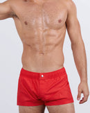 Frontal view of a masculine model wearing the PRIME RED Mini Shorts for men by DC2 Miami, a premium swimwear brand. These ultra-short beach shorts feature a bold red color, an elastic waistband with an adjustable internal drawstring, and a sleek fitted cut, making them perfect for bold summer looks, beach days, and poolside lounging.