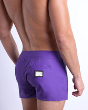 Side view of the PURPLE MACHINE Summer Beach Shorts with dual zippered pockets for men featuring a solid purple color is designed by BANG! Clothes in Miami.