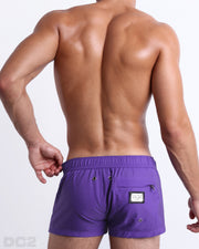 Back view of the PURPLE MACHINE beach Mini Shorts in a solid vibrant purple color, complete with a back zippered pocket, designed by DC2 a capsule brand by BANG! Clothes based in Miami.
