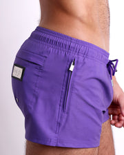 Side view of the PURPLE MACHINE swimsuit Poolside Shorts men’s shorter length shorts with side zipper pocket featuring a bright purple color. These high-quality swimwear bottoms by DC2, a men’s beachwear brand from Miami.