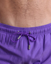Close-up view of the PURPLE MACHINE men’s summer shorts, showing purple cord with custom branded silver cord ends, and matching custom eyelet trims in silver.