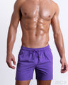 Male model wearing the PURPLE MACHINE Resort Shorts, premium swimwear in a vibrant purple color for men. These high-quality swimwear bottoms by DC2, a men’s beachwear brand from Miami.