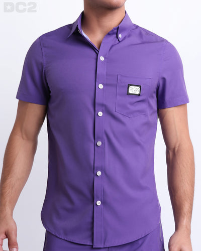 This is a front view of a male model looking sexy in a PURPLE MACHINE stretch shirt for men. The shirt is a vibrant violet color on the left pocket. It's a premium quality button-up top made by DC2, a Miami-based men's beachwear brand.