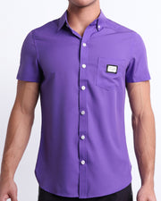 This is a front view of a male model looking sexy in a PURPLE MACHINE Stretch Shirt and a the DARK KNIGHT Beach Shorts for men.