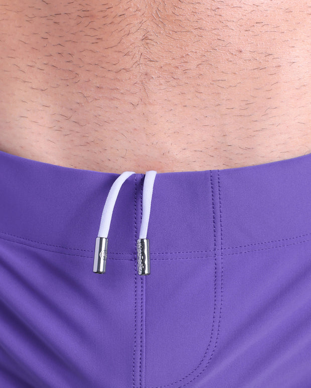 Close-up view of men’s summer beach shorts by DC2 clothing brand, showing white cord with custom branded metallic silver cord ends.
