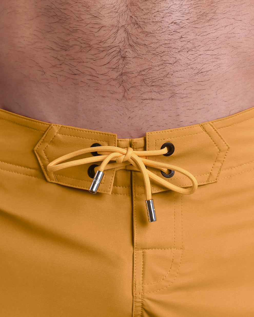 Close-up view of men’s summer Flex shorts by DC2 clothing brand, showing  yellow color cord with custom-branded golden cord ends, and matching custom eyelet trims in gold.
