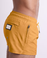 Side view of the RETRO MUSTARD swimsuit Poolside Shorts men’s shorter length shorts with side zipper pocket featuring a sunny yellow color. These high-quality swimwear bottoms by DC2, a men’s beachwear brand from Miami.