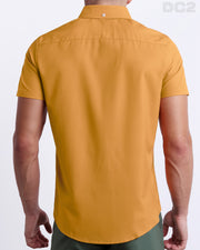 A male model is seen from the back wearing a white RETRO MUSTARD a Hawaiian shirt from DC2, a Miami-based men’s beachwear brand. 