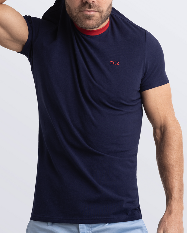 A model adjusting a navy blue Pima cotton t-shirt with a bold red collar, showcasing the breathable, lightweight fabric ideal for summer beachwear and street style. Part of the DC2 Miami men&