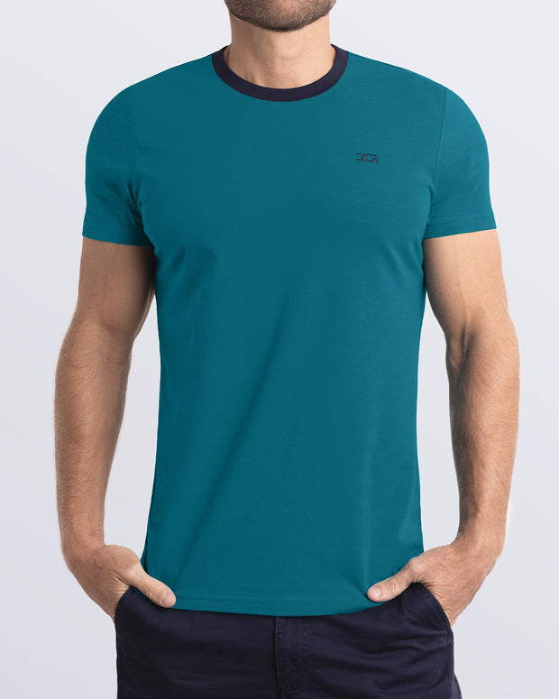 A model wearing the RING ON IT TEAL, a teal Pima cotton t-shirt with a bold dark blue collar, showcasing the breathable, lightweight fabric ideal for summer beachwear and street style. Part of the DC2 Miami men&