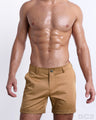 Front view of a male model wearing SAFARI BROWN men's chino shorts in a solid tan brown color with reversible cuffs exposing a fun print by DC2 a BANG! Miami Clothes capsule brand.