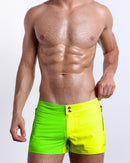 Male model wearing SINGLE BILINGUAL (NEON YELLOW/GREEN) Beach Shorts, premium swimwear with a stylish color block design in bright neon yellow and lime green colors for men. These high-quality swimwear bottoms by BANG! Clothes, a men’s beachwear brand from Miami.