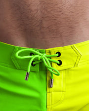 Close-up view of men’s summer Flex shorts by BANG! clothing brand, showing bright lime green color cord with custom-branded golden cord ends, and matching custom eyelet trims in gold.