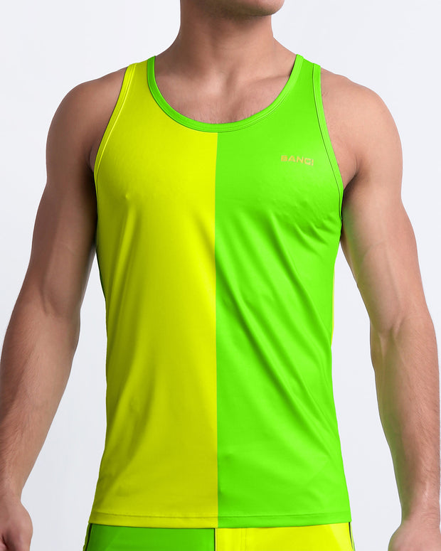 Male model wearing SINGLE BILINGUAL (NEON YELLOW/GREEN) Summer Tank Top, a premium quality top with a stylish color block design in bright neon yellow and lime green colors for men. This high-quality tank top by BANG! Clothes, a men’s beachwear brand from Miami.