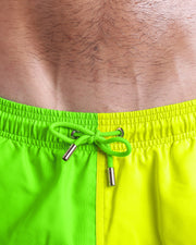 Close-up view of inseam and details of SINGLE BILINGUAL (NEON YELLOW/GREEN) swimsuit for men, with lime green color cord and custom branded golden cord-ends, and matching custom eyelet trims in gold.