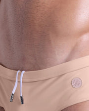 Close-up view of the SKINNY DIP men’s drawstring briefs showing white cord with custom branded metallic silver cord ends, and matching custom eyelet trims in silver.