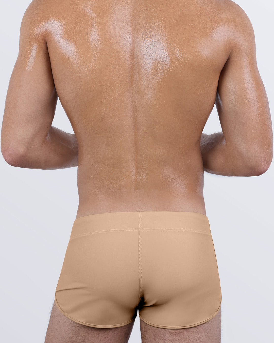Back view of DC2 SKINNY DIP (MEDIUM) swim shorts in tan color showcasing retro-inspired curved hem and fitted design.