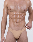  Male model wearing DC2 BANG Skinny Dip (Medium) swim thong in tan beige – men's minimal coverage swimsuit with sleek low-rise cut.