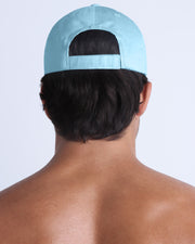 The SKY BLUE Chillax Cap, modeled here, is in blue. Its adjustable velcro strap at the back ensures a perfect fit for any head size.