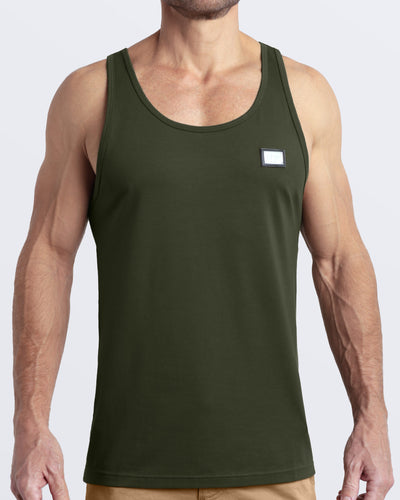 Frontal view of male model wearing the SLICK GREEN in a solid dark green color casual gym tank top for men by the DC2 brand of men's beachwear from Miami.